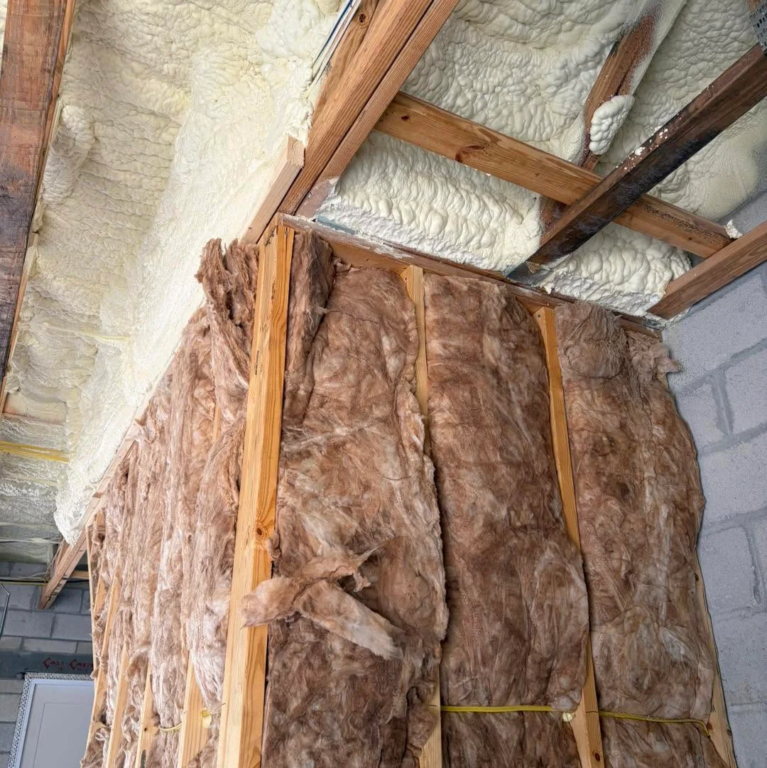 Combination insulation installation featuring fiberglass batt insulation in wall studs and spray foam along the ceiling joists
